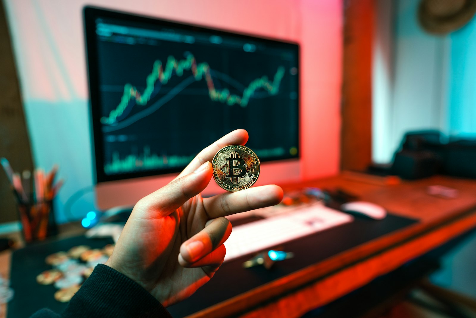 A hand holding a coin in front of a computer screen