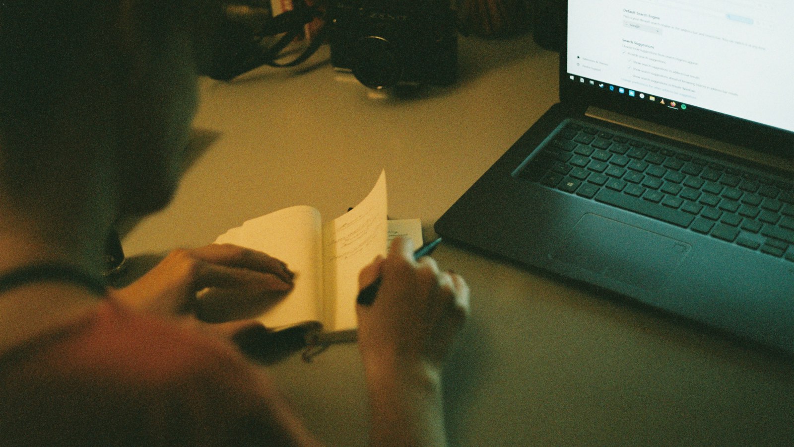 Person reviewing a document next to a laptop