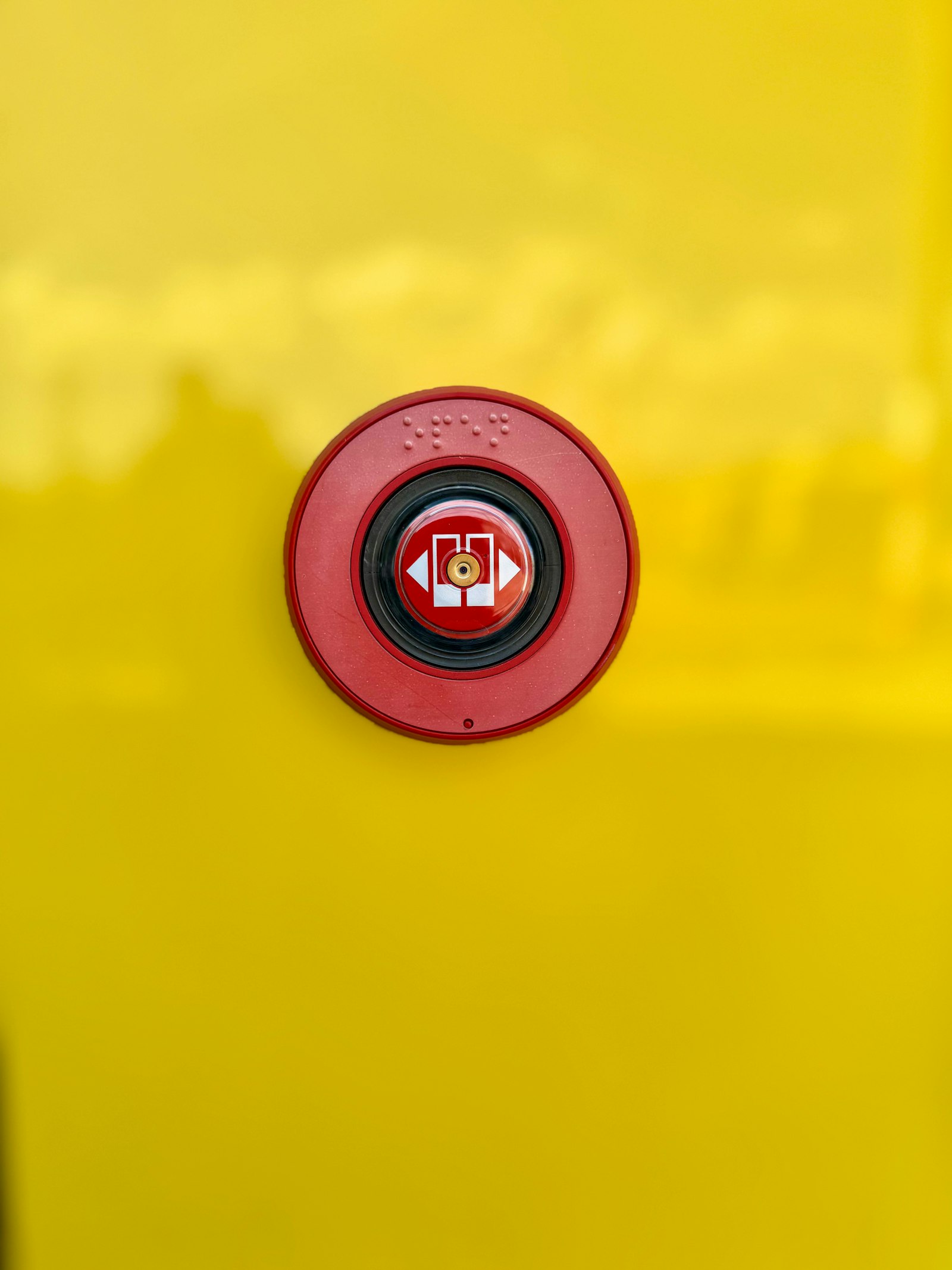 A red emergency button on a bright yellow background