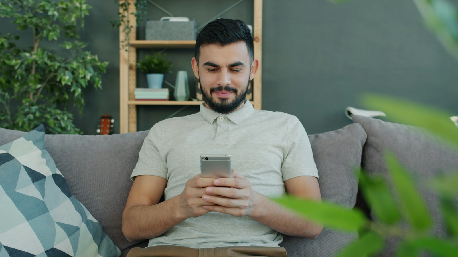 A man sitting on a couch casually using a smartphone